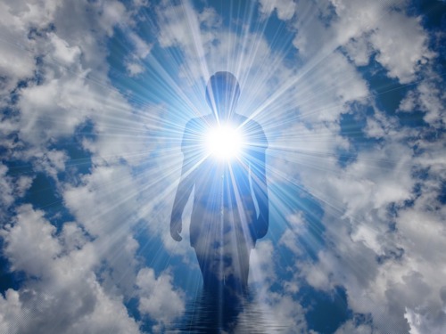 Human figure standing in front of clouds and rays of light