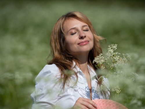 Woman holding flowers while standing in a grassy meadow