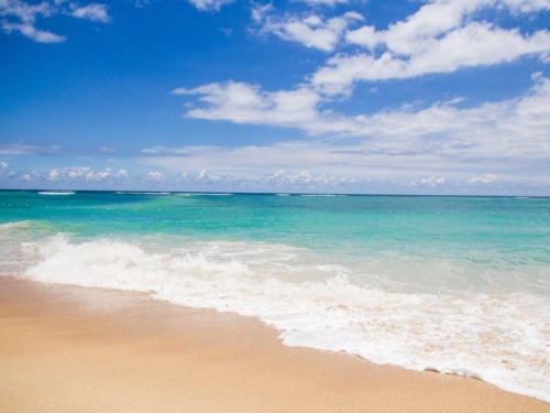 Turquoise ocean water with waves and a sandy beach