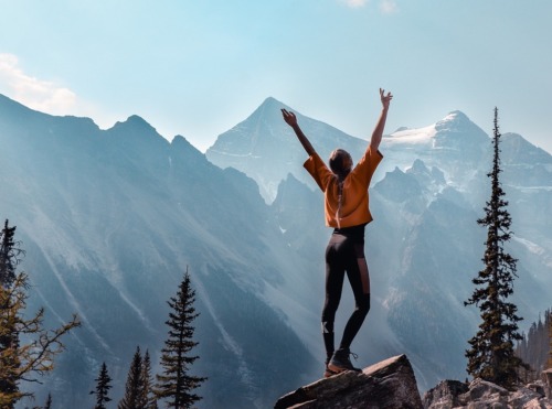 Woman, with arms outstretched, on top of a mountain